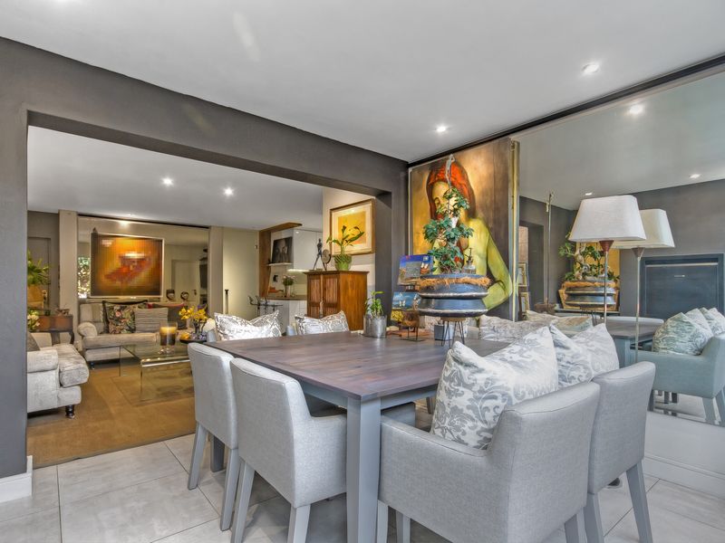 Spacious open-plan living and dining area featuring modern tiled flooring, recessed downlighting, and a large feature mirrored wall.