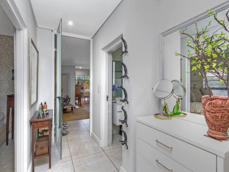 A bright, well-maintained hallway featuring tiled flooring, recessed lighting, and a glass door leading to the main living area.