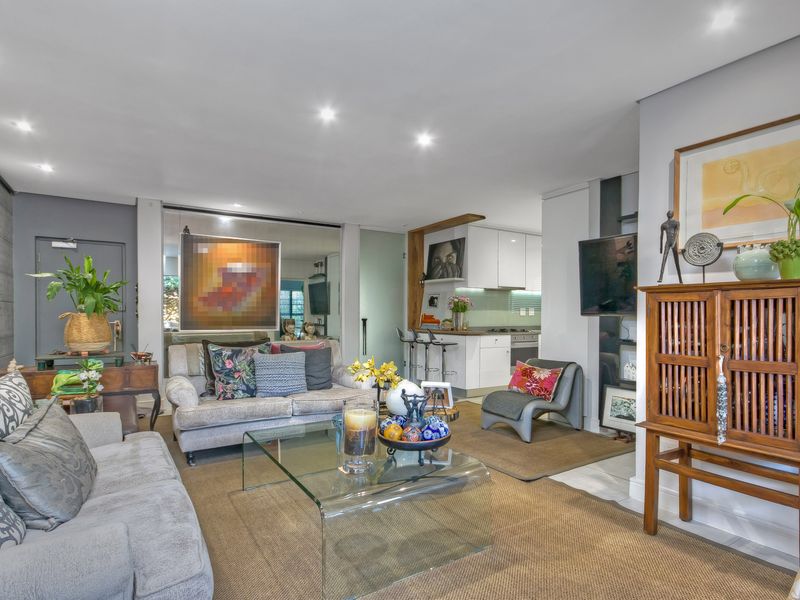 Open-plan living area featuring a modern kitchen with integrated appliances, recessed lighting, and a decorative mirrored wall panel.