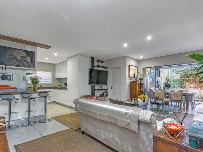 Spacious open-plan living area featuring a modern kitchen with breakfast bar, tiled floors, and seamless flow to an outdoor patio through sliding glass doors.