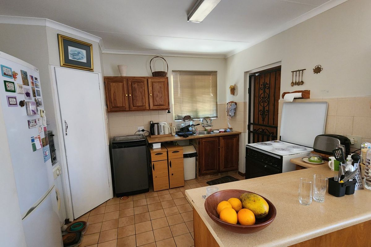 Functional kitchen featuring wooden cabinetry, tiled flooring, a built-in stove, and a breakfast counter, offering a practical layout for daily meal preparation.