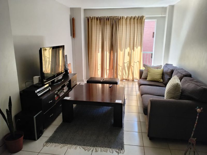 A living room featuring tiled flooring and a sliding glass door with curtains, providing access to an outdoor area.