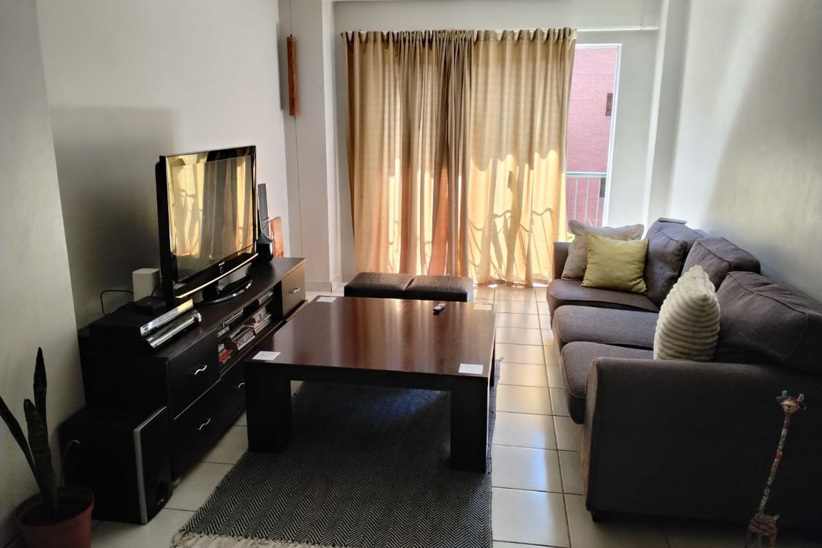 A living room featuring tiled flooring and a sliding glass door with curtains, providing access to an outdoor area.