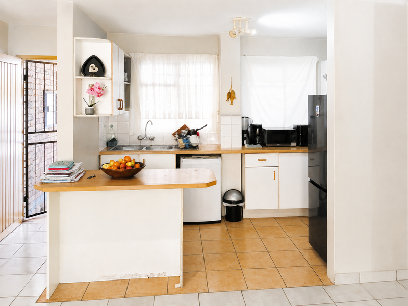A functional kitchen featuring tiled flooring, built-in cabinetry, a double sink, and a breakfast bar, offering a practical layout for daily use.