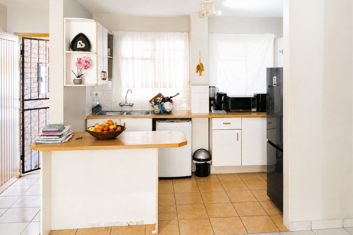 A functional kitchen featuring tiled flooring, built-in cabinetry, a double sink, and a breakfast bar, offering a practical layout for daily use.