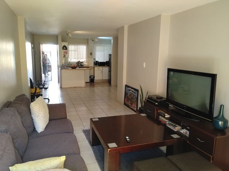 Open plan living area and kitchen featuring tiled flooring and functional cabinetry, providing a combined space for relaxation and meal preparation.