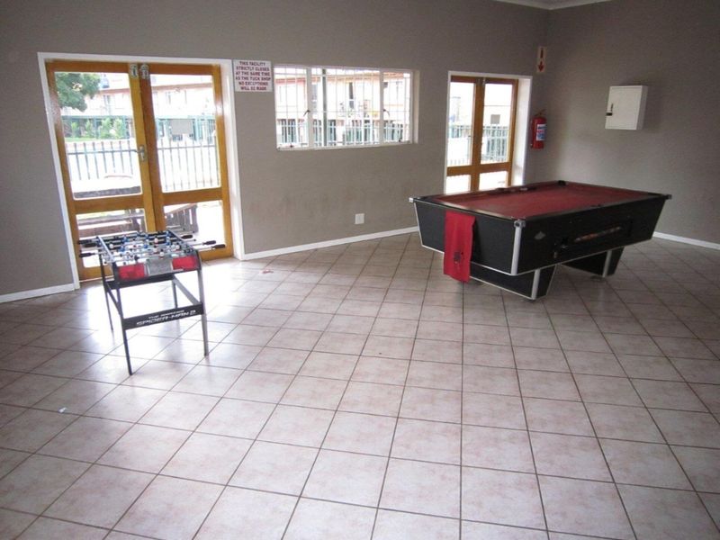 A communal clubhouse area featuring tiled flooring, double glass doors providing outdoor access, and basic wall-mounted safety equipment.