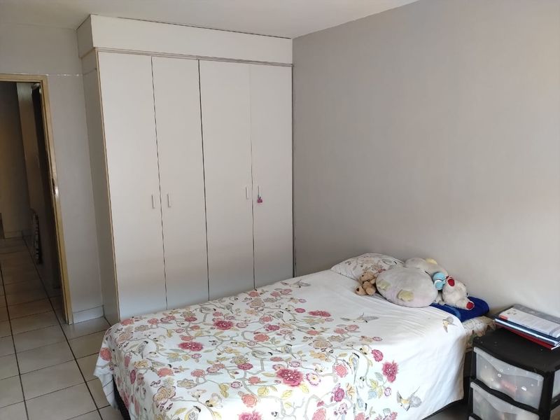 A functional bedroom featuring built-in cupboards and tiled flooring, offering a clean and neutral space.