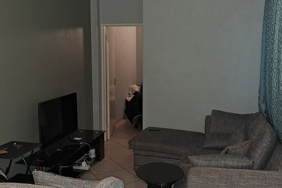 A living room area featuring tiled flooring and neutral wall tones, providing a functional space for relaxation.