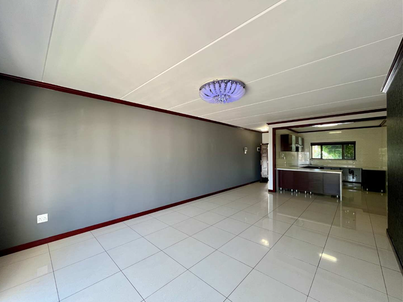 Spacious open-plan living and kitchen area featuring polished tile flooring, modern cabinetry, and a clean, neutral aesthetic ready for personalization.