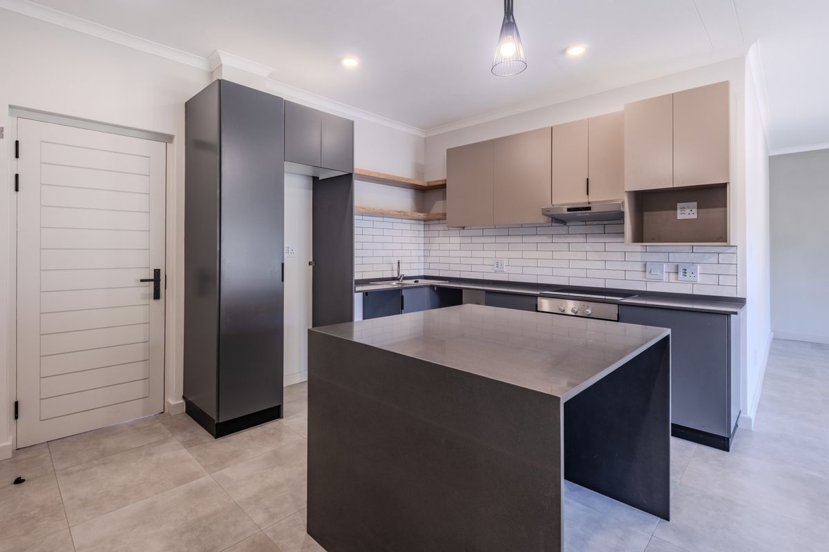 Modern kitchen featuring a central island, sleek two-tone cabinetry, subway tile backsplash, and integrated appliances in a clean, contemporary layout.