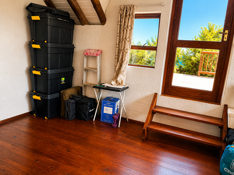 A bedroom space featuring warm timber flooring, exposed wooden rafters, and direct access to an outdoor balcony through a timber door.