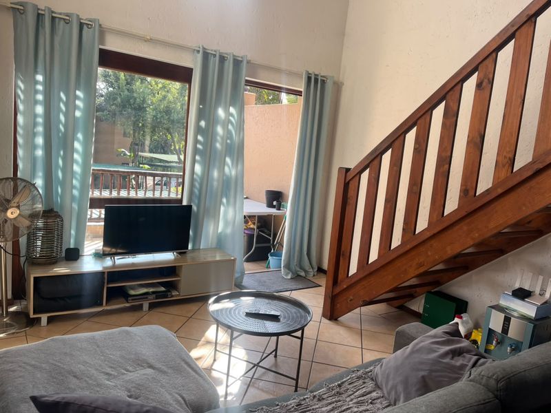 Living room featuring tiled flooring, a wooden staircase, and sliding glass doors providing access to an outdoor patio area.