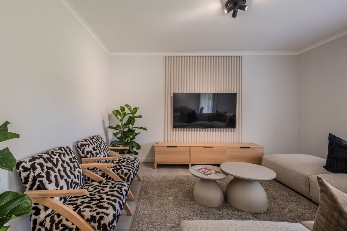 A modern living room featuring a stylish slatted timber feature wall and contemporary ceiling lighting, creating a warm and inviting atmosphere.
