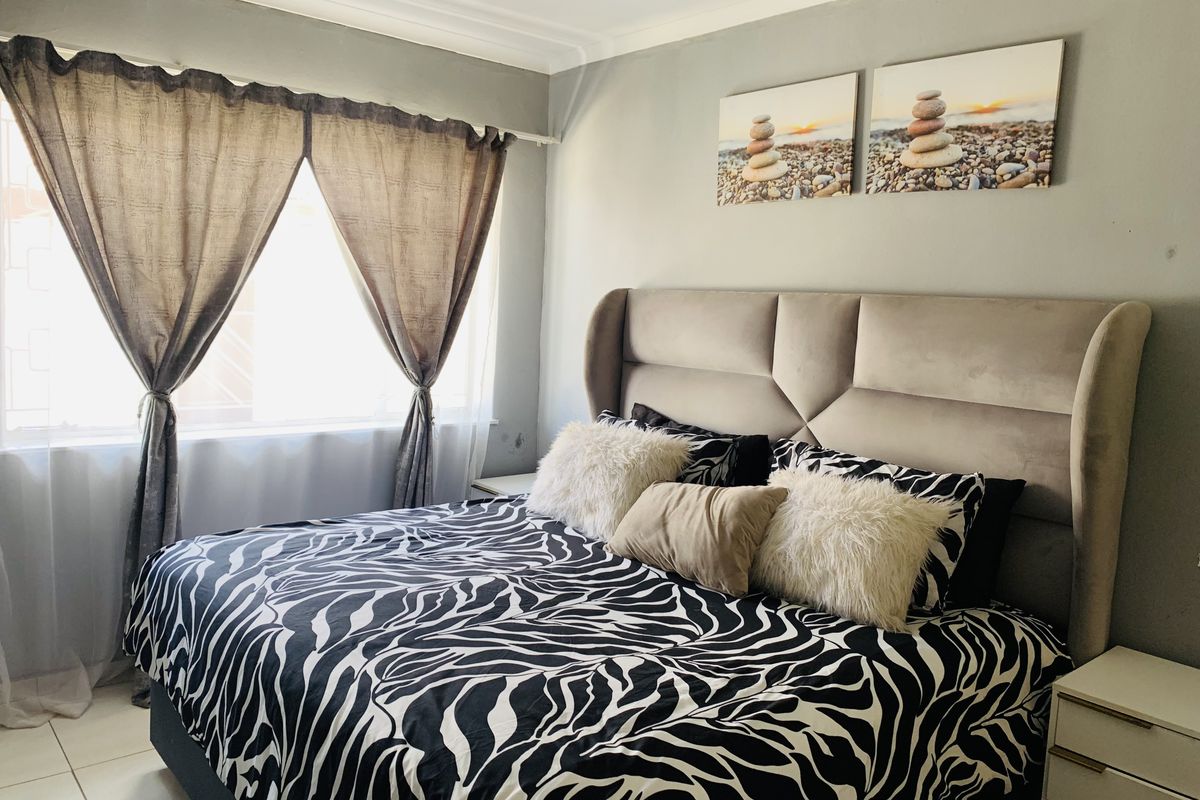 A well-maintained bedroom featuring neutral wall tones, tiled flooring, and decorative cove cornicing, providing a comfortable and functional living space.