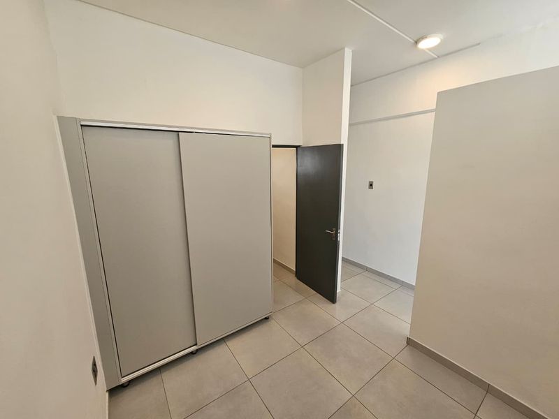 A clean, empty bedroom featuring neutral tiled flooring and a built-in sliding door wardrobe, offering a versatile space ready for personalization.