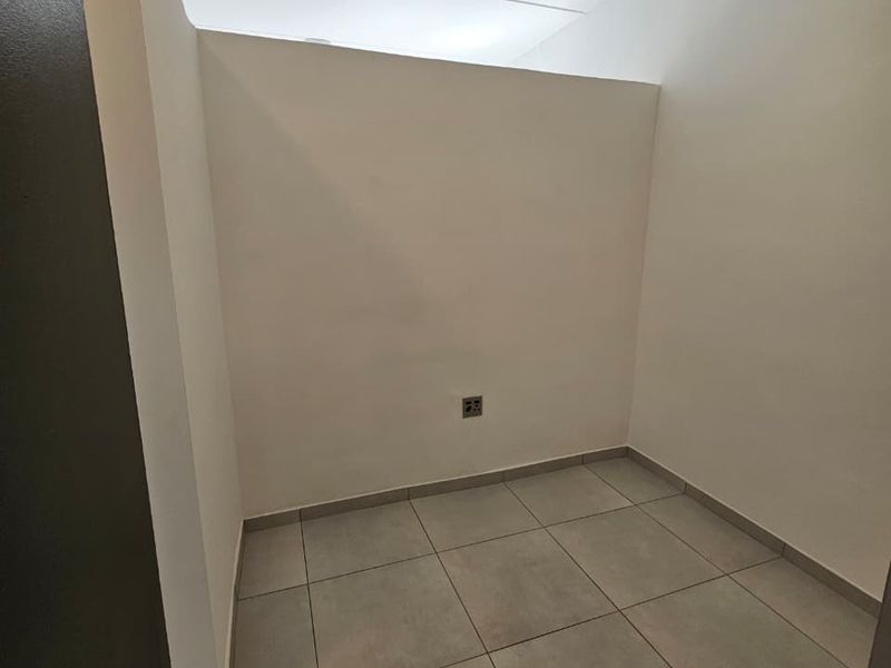 A clean, empty utility space featuring neutral floor tiles and a single electrical outlet, suitable for storage or a small home office.