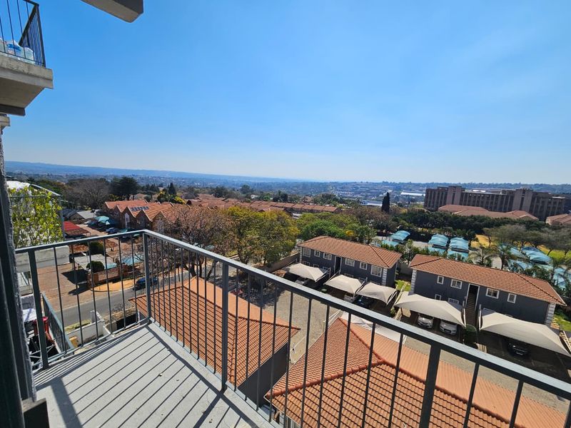 An elevated balcony featuring a metal balustrade and offering expansive views over the surrounding residential complex and neighborhood.