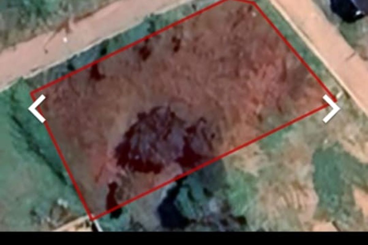 An aerial view of a vacant residential plot of land with boundary markers indicated.