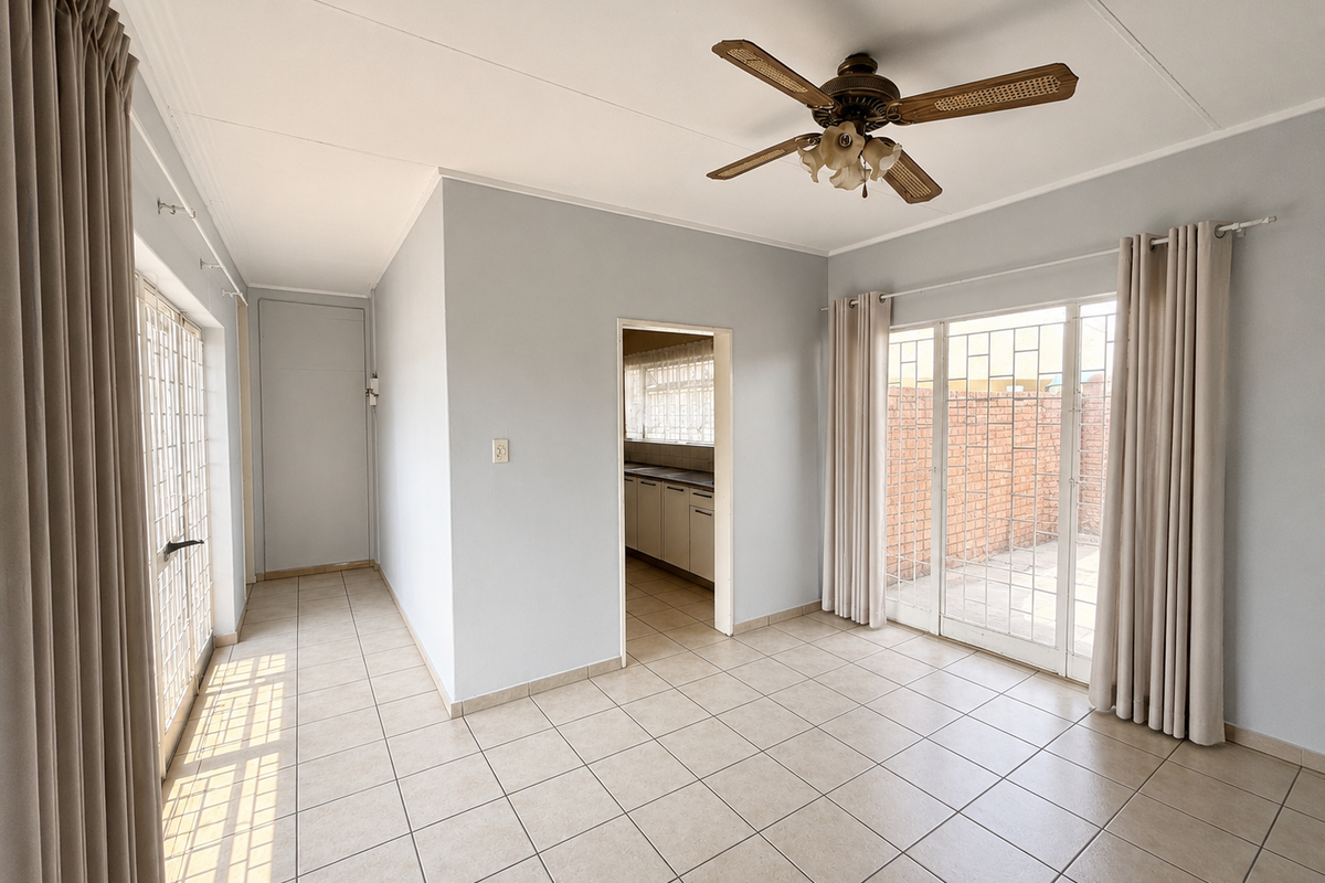 Bright and spacious living area featuring neutral ceramic floor tiles, a ceiling fan, and sliding glass doors providing access to the outdoor space.