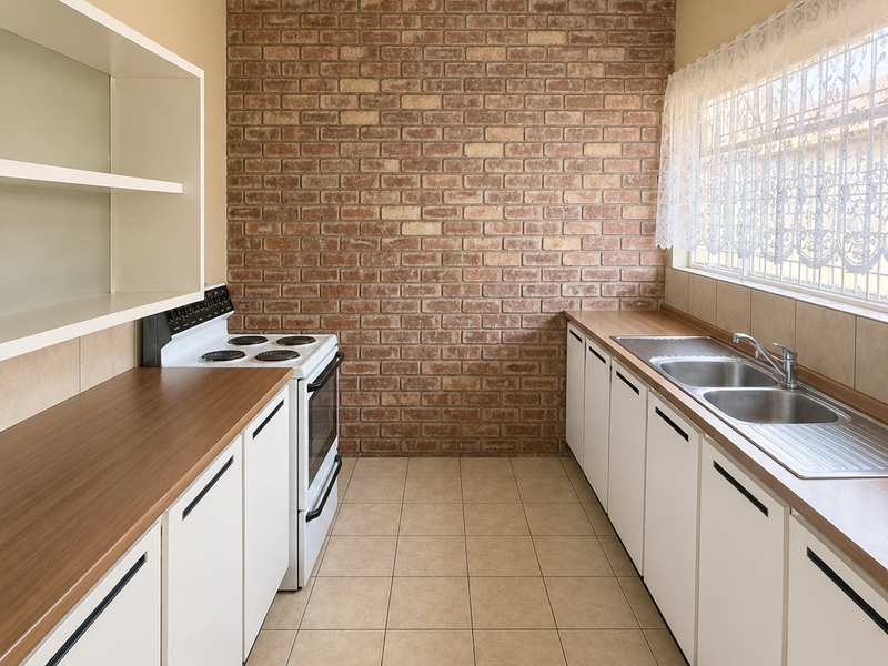 A functional galley-style kitchen featuring an exposed brick feature wall, white cabinetry, laminate countertops, and a double bowl stainless steel sink.