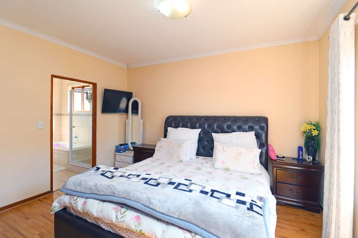 A bedroom featuring laminate flooring and direct access to an en-suite bathroom with a bathtub.
