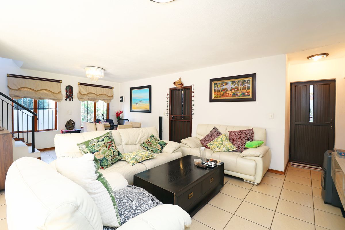 Spacious living room featuring tiled flooring, a staircase, and neutral walls, providing a comfortable and functional area for relaxation.