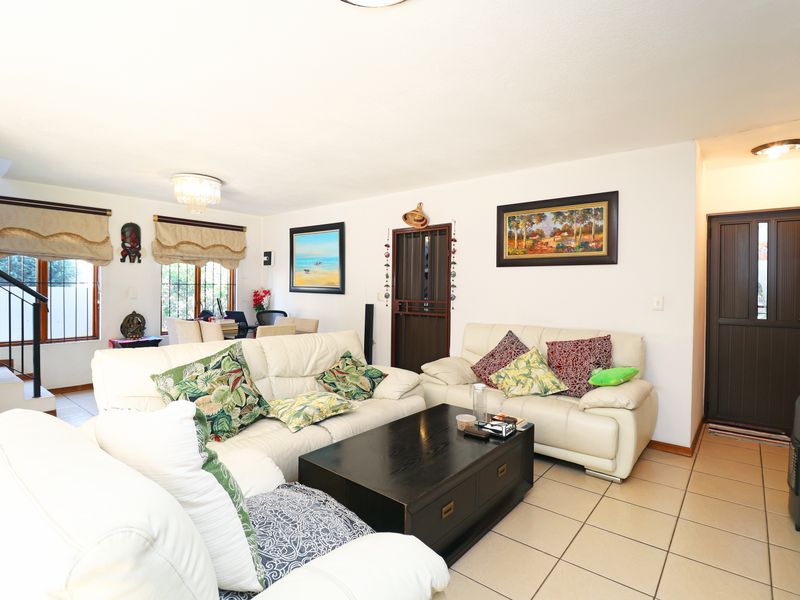 Spacious living room featuring tiled flooring, a staircase, and neutral walls, providing a comfortable and functional area for relaxation.