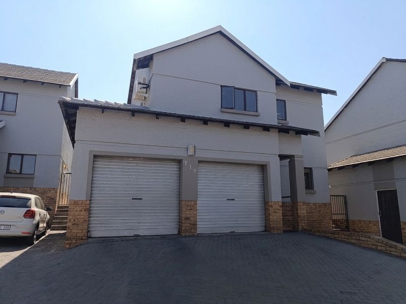 Front elevation of a double-story townhouse featuring a double garage with roller shutter doors and a paved driveway.