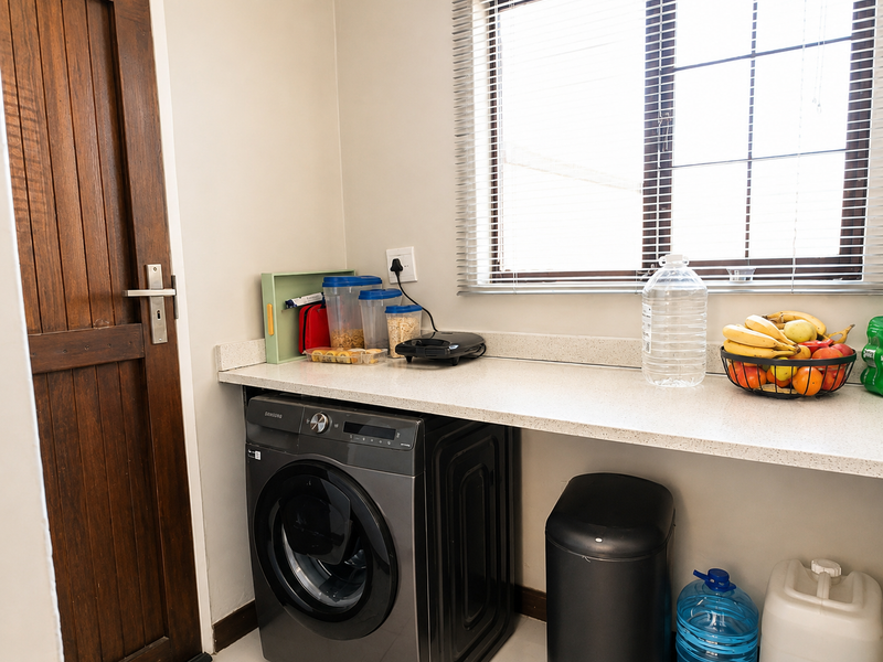 A functional laundry area featuring a stone countertop, a timber door, and a window with venetian blinds.