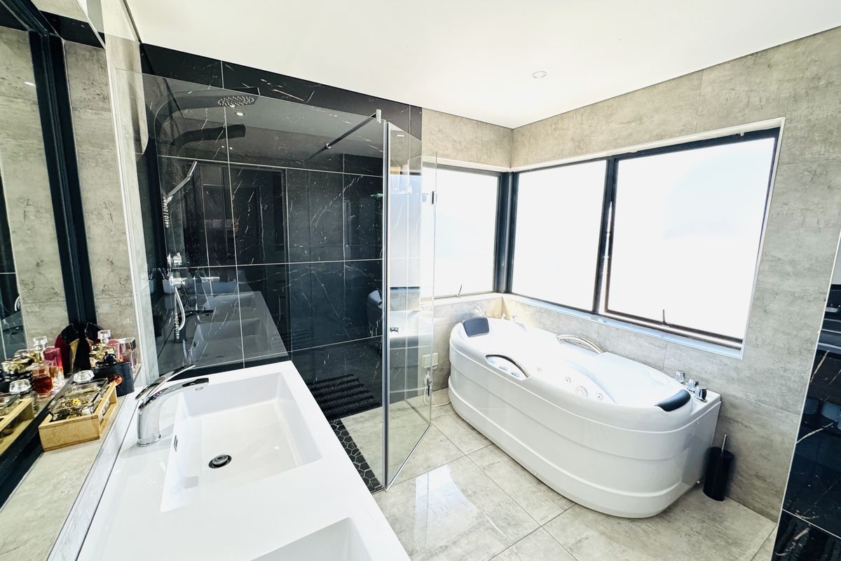 Modern bathroom featuring a double vanity, a spacious walk-in shower with black marble-effect tiles, and a contemporary jetted bathtub under large windows.