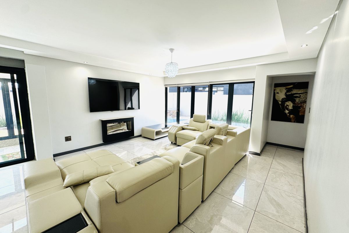 Modern living room featuring large format tiled flooring, recessed ceiling lighting, a built-in fireplace, and expansive sliding glass doors leading to the exterior.