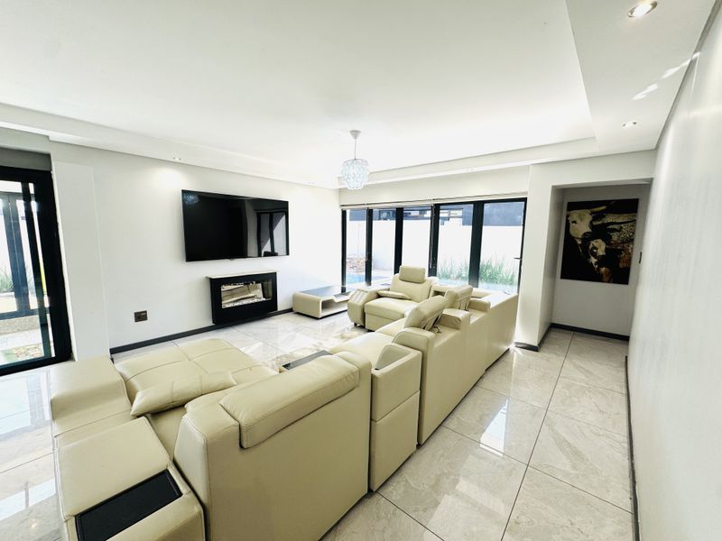 Modern living room featuring large format tiled flooring, recessed ceiling lighting, a built-in fireplace, and expansive sliding glass doors leading to the exterior.