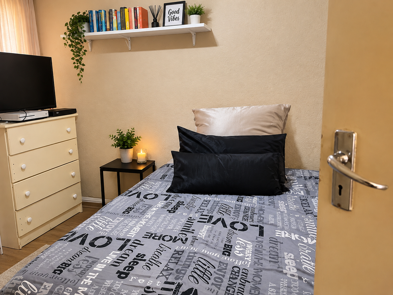 A cozy bedroom featuring a wall-mounted display shelf and standard interior door hardware.