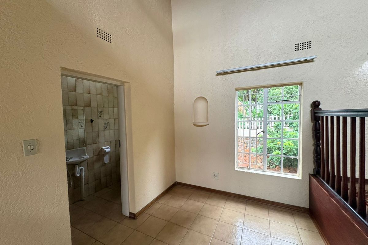 An empty bedroom featuring high vaulted ceilings, tiled flooring, a built-in wall niche, and direct access to an en-suite bathroom.