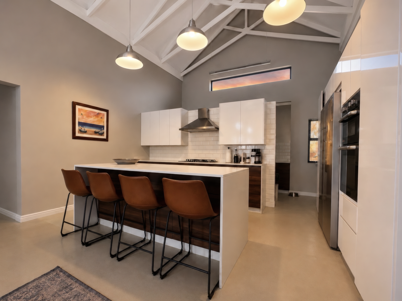 Modern kitchen featuring a large island, high-gloss cabinetry, built-in appliances, subway tile backsplash, and a striking vaulted ceiling with pendant lighting.
