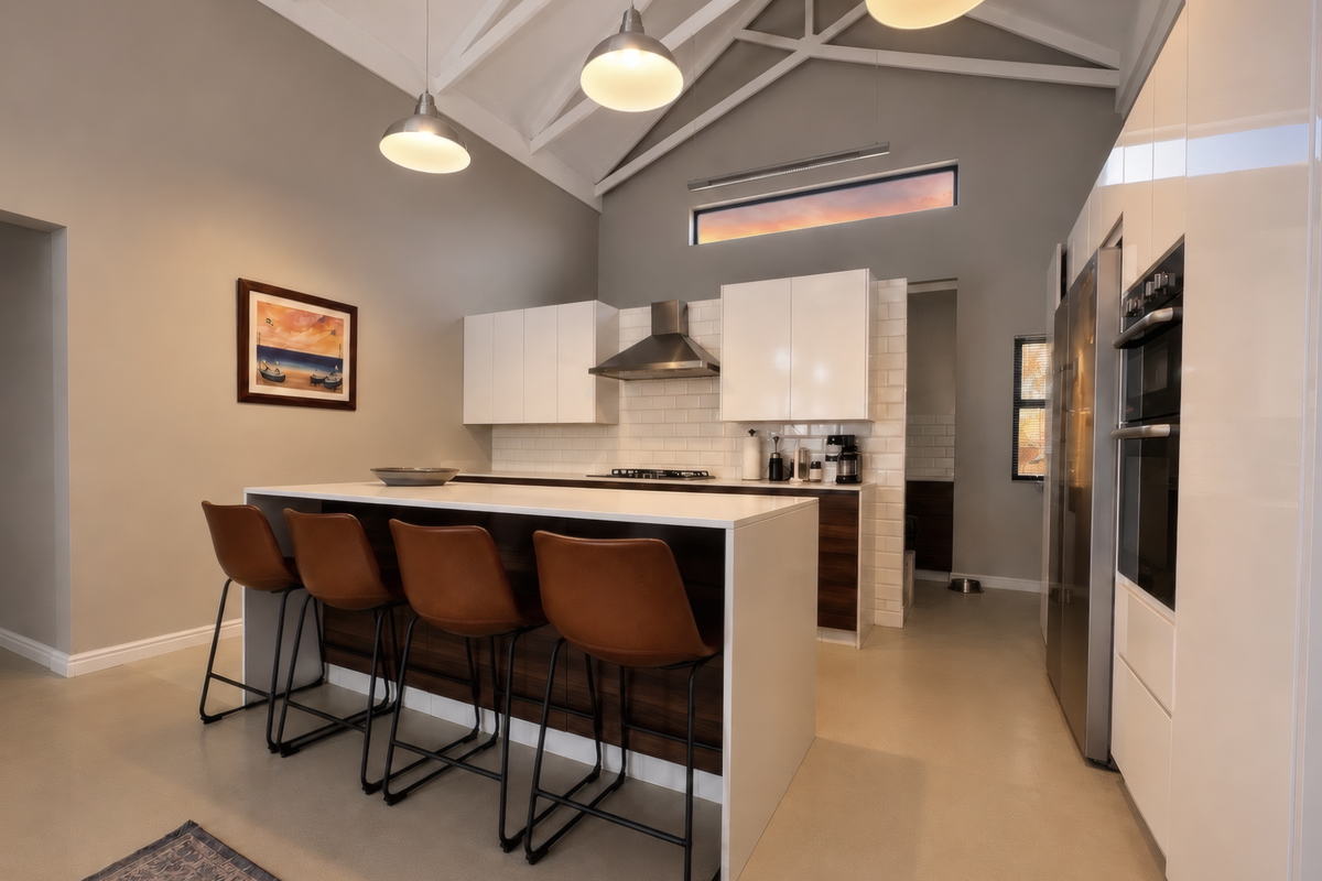 Modern kitchen featuring a large island, high-gloss cabinetry, built-in appliances, subway tile backsplash, and a striking vaulted ceiling with pendant lighting.