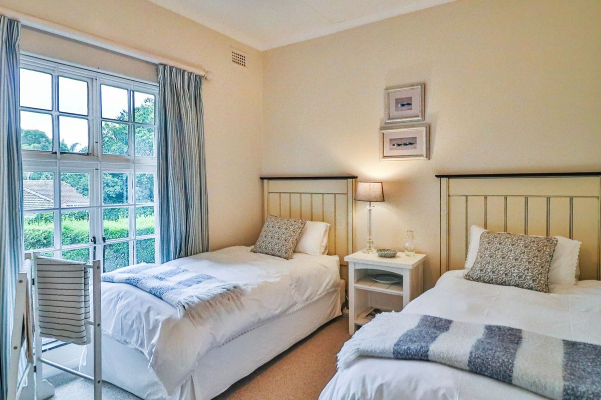 A well-lit bedroom featuring a large multi-pane window with garden views and neutral wall finishes.