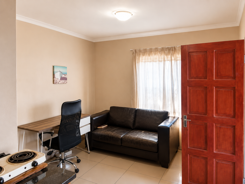 A functional bedroom featuring tiled flooring, neutral wall finishes, and a solid timber panel door, providing a versatile space for rest or work.