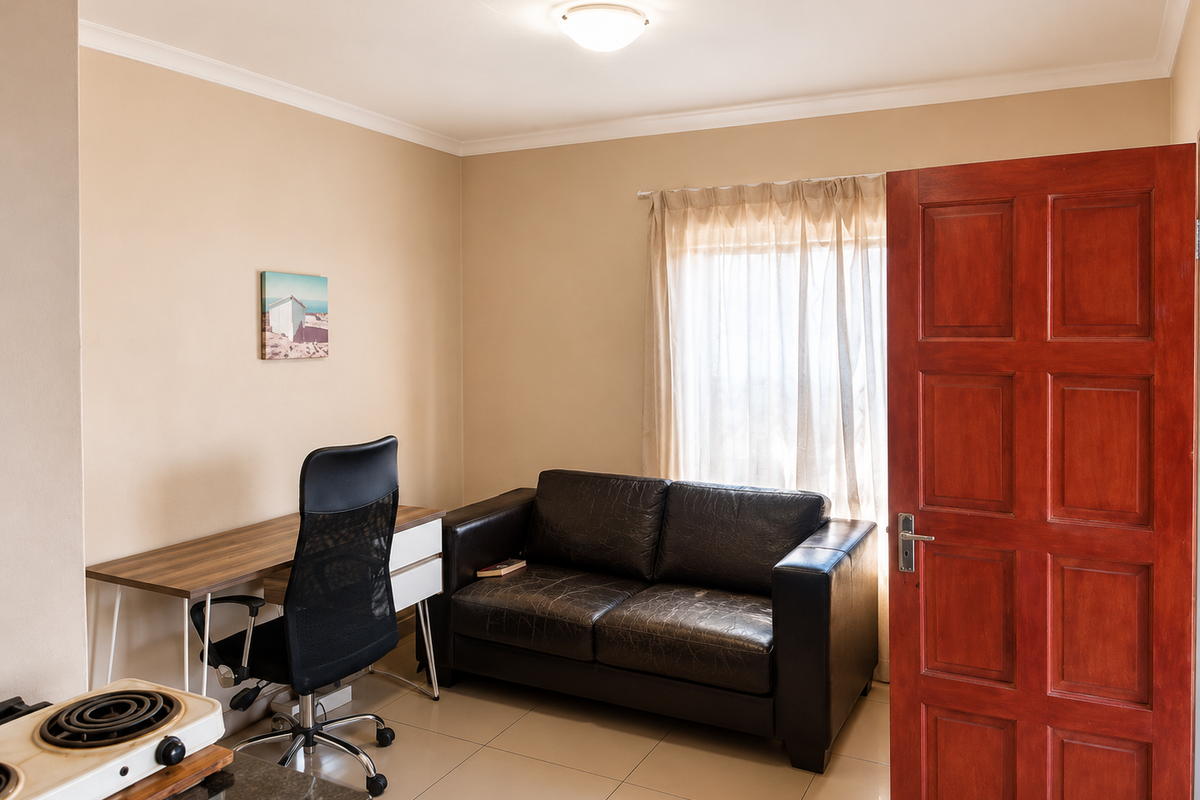 A functional bedroom featuring tiled flooring, neutral wall finishes, and a solid timber panel door, providing a versatile space for rest or work.