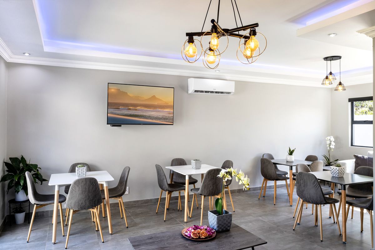 A modern, well-lit living area featuring tiled flooring, recessed cove lighting, and a wall-mounted air conditioning unit.