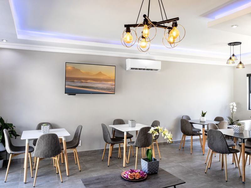 A modern, well-lit living area featuring tiled flooring, recessed cove lighting, and a wall-mounted air conditioning unit.