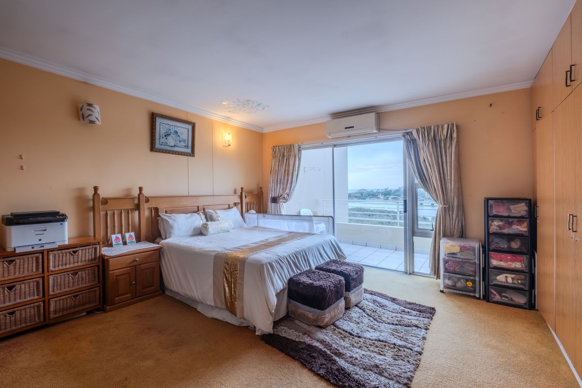 Spacious bedroom featuring built-in cupboards, wall-mounted air conditioning, and direct access to a private balcony with scenic views.