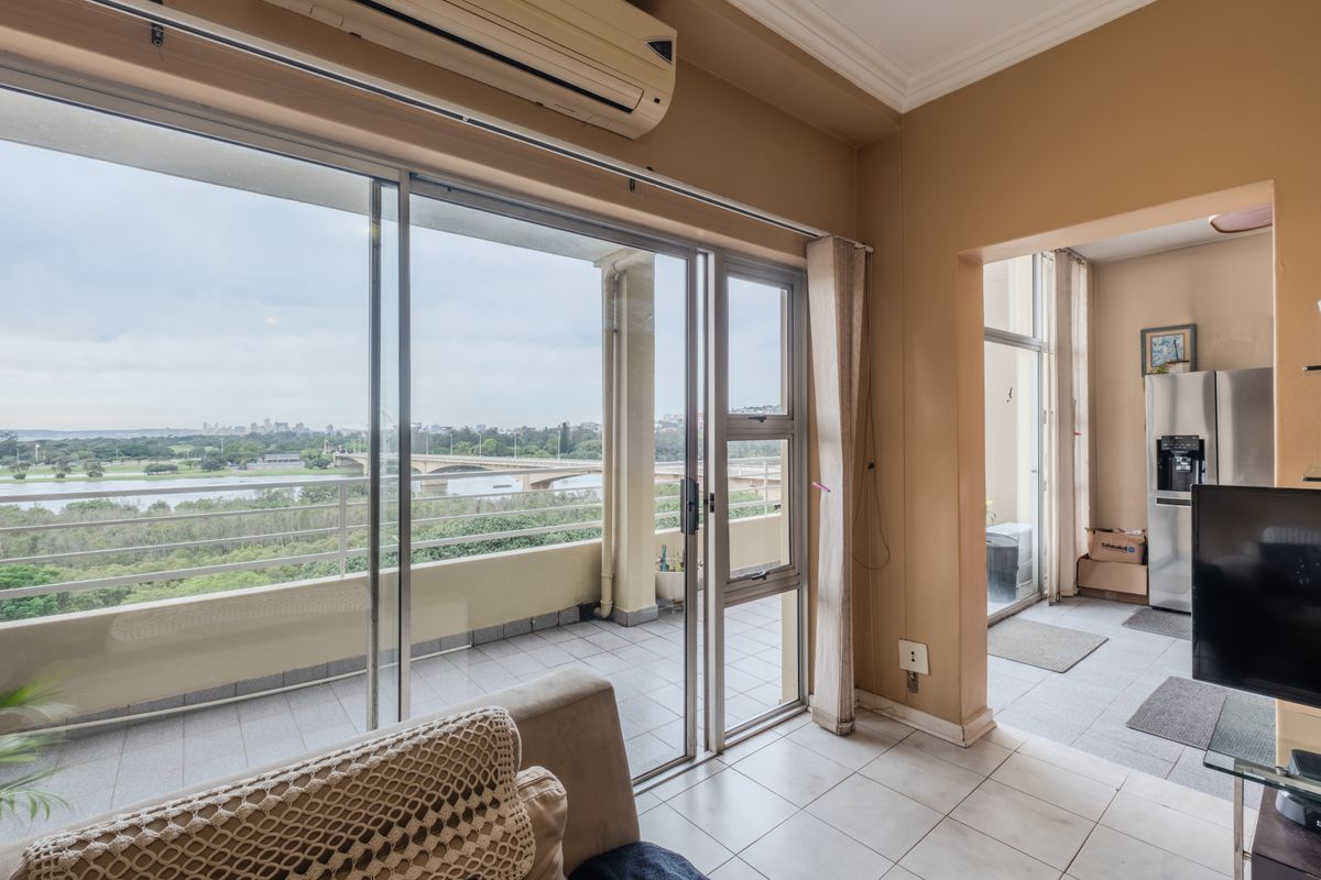 Living room featuring large sliding glass doors leading to a balcony with scenic views, tiled flooring, and a wall-mounted air conditioning unit.