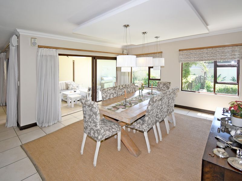 Spacious dining room featuring tiled flooring, recessed ceiling detail, and large sliding glass doors providing seamless access to the outdoor patio area.