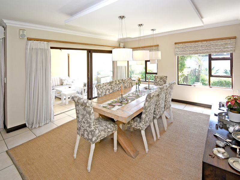 Spacious dining room featuring tiled flooring, recessed ceiling detail, and large sliding glass doors providing seamless access to the outdoor patio area.