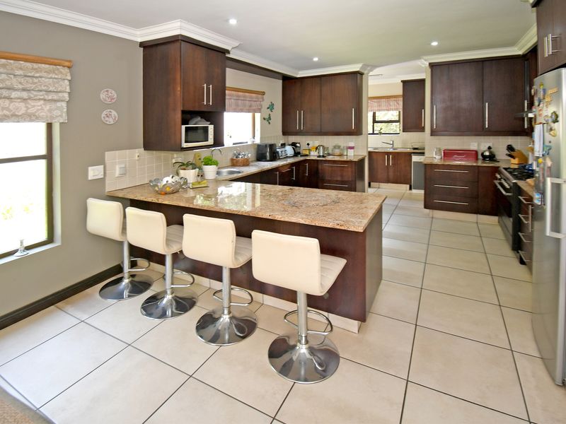 Spacious kitchen featuring dark wood cabinetry, granite countertops, a breakfast bar, and tiled flooring, offering a functional layout with ample storage and workspace.