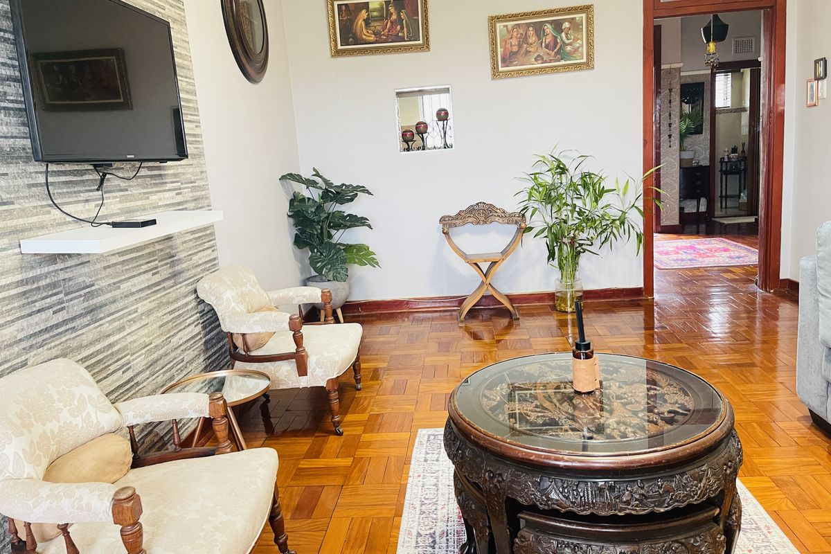 A well-maintained living room featuring polished parquet flooring and a textured stone-clad feature wall with a mounted television shelf.