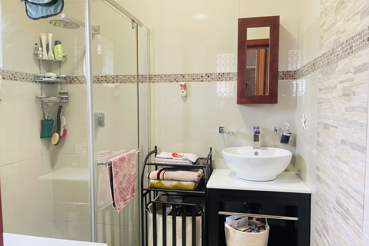 A modern bathroom featuring a glass-enclosed shower, a contemporary vessel sink on a vanity cabinet, and decorative mosaic tile accents.