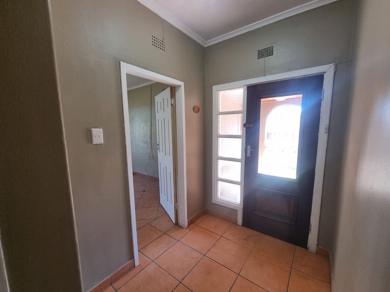 A functional entrance hall featuring tiled flooring, a timber front door with side light, and neutral wall finishes.
